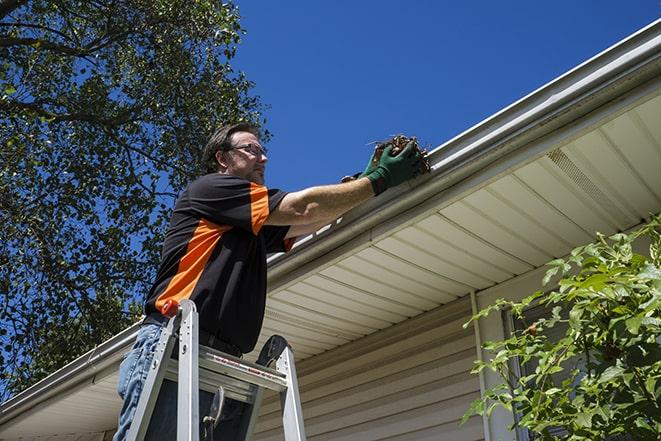 a worker using a ladder to fix a damaged gutter in Crestview